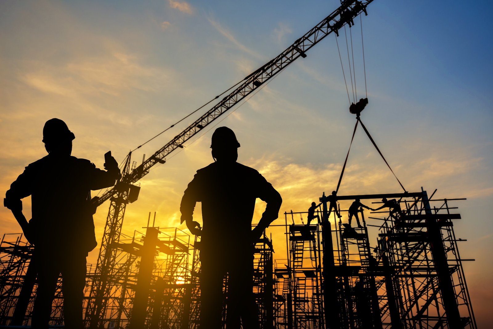 Construction workers silhouette at a building site during sunset